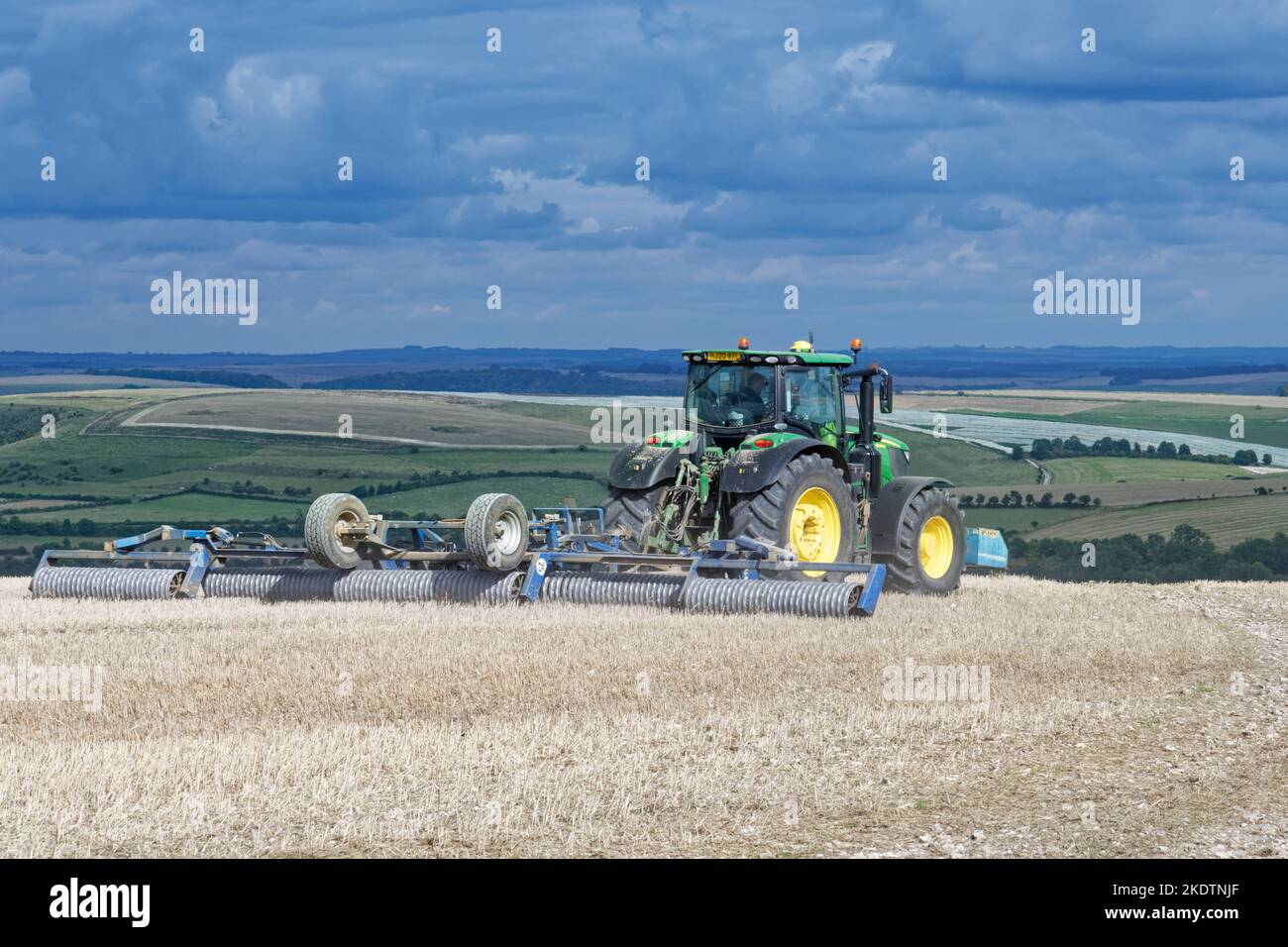 Tracteur tractant un rouleau Cambridge / rouleau à Ridgeed / Cultipacker sur un champ de culture arable sans labour sur une terre de craie exposée, Cold Kitchen Hill, près de Monkto Banque D'Images