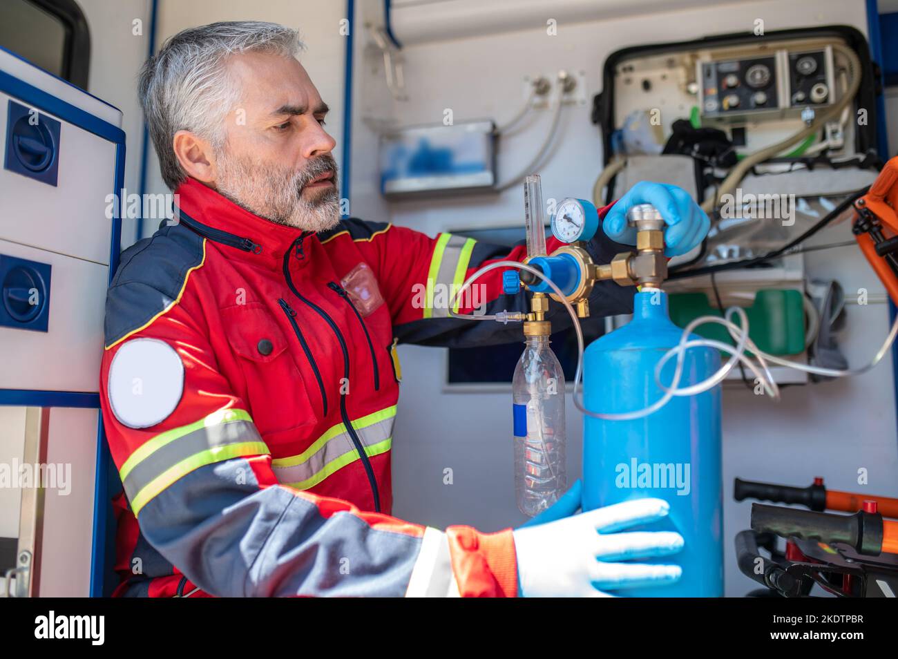 Ambulanciers paramédicaux concentrés préparant l'appareil respiratoire pour l'oxygénothérapie Banque D'Images