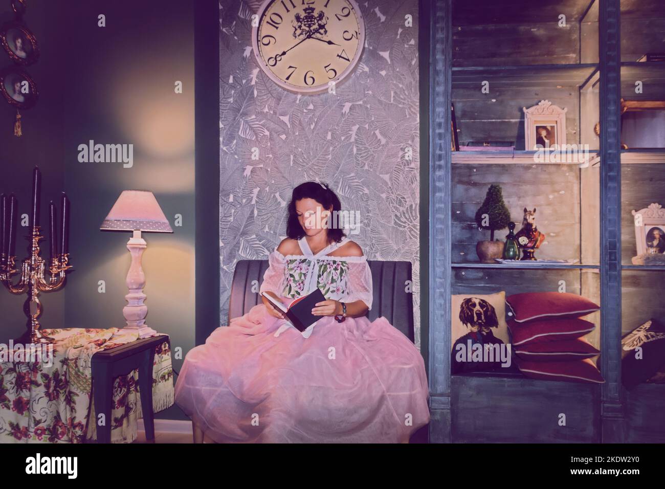 Une fille dans une robe rose à l'ancienne est en train de lire un livre., art numérique intérieur Vintage. Style rétro. Banque D'Images