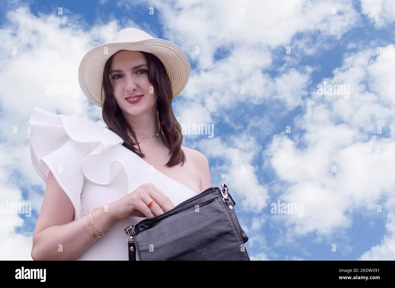 Femme heureuse détendue souriant, posant dans le chapeau, ciel bleu comme arrière-plan et espace de copie. Banque D'Images