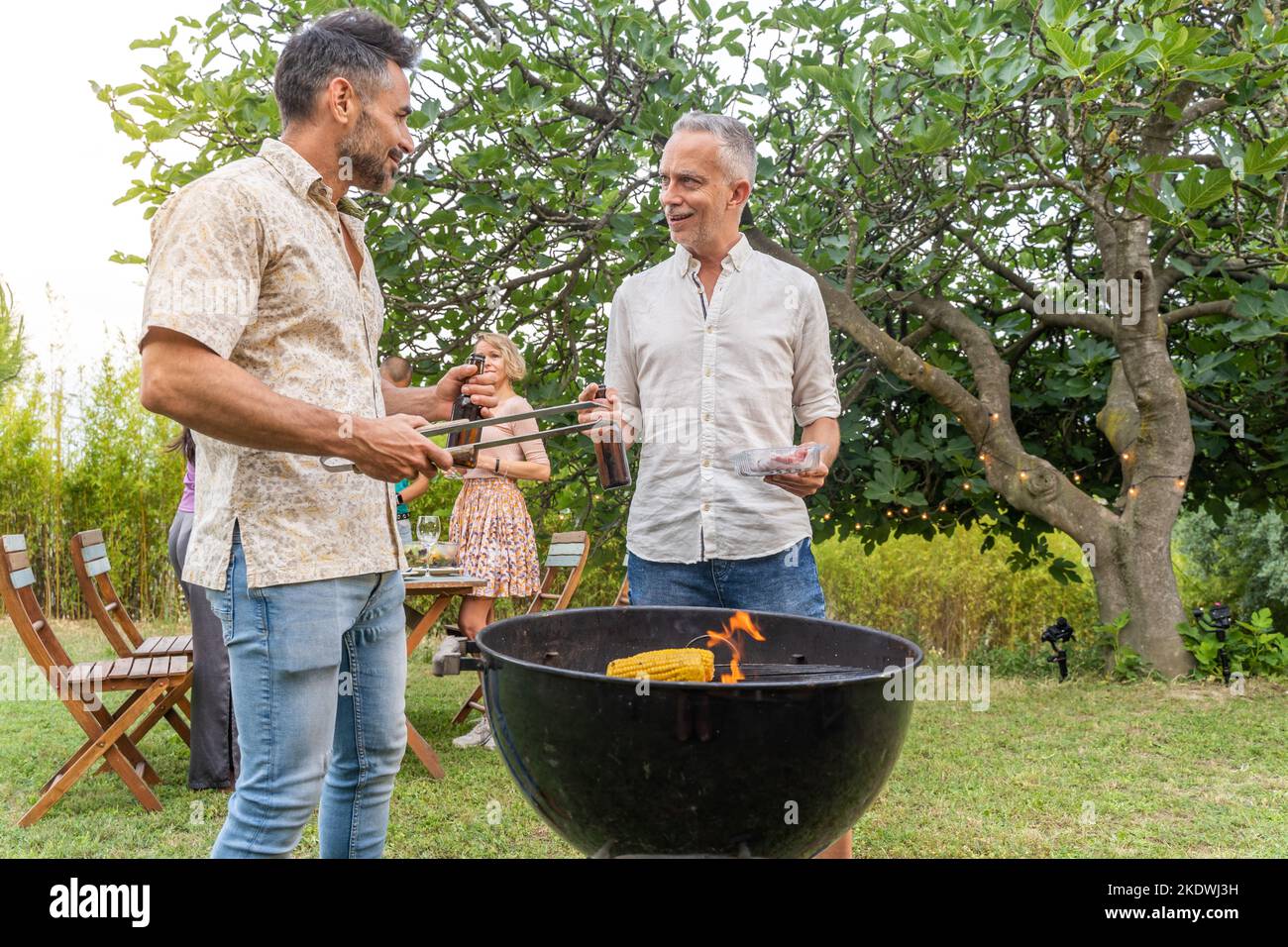 Des amis multiculturels matures autour du barbecue souriant heureux et riant ensemble. Concept de joie. Banque D'Images