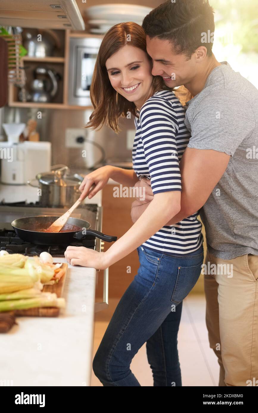 Cuisinez leur repas préféré ensemble. Un jeune couple affectueux cuisant un repas ensemble dans sa cuisine. Banque D'Images