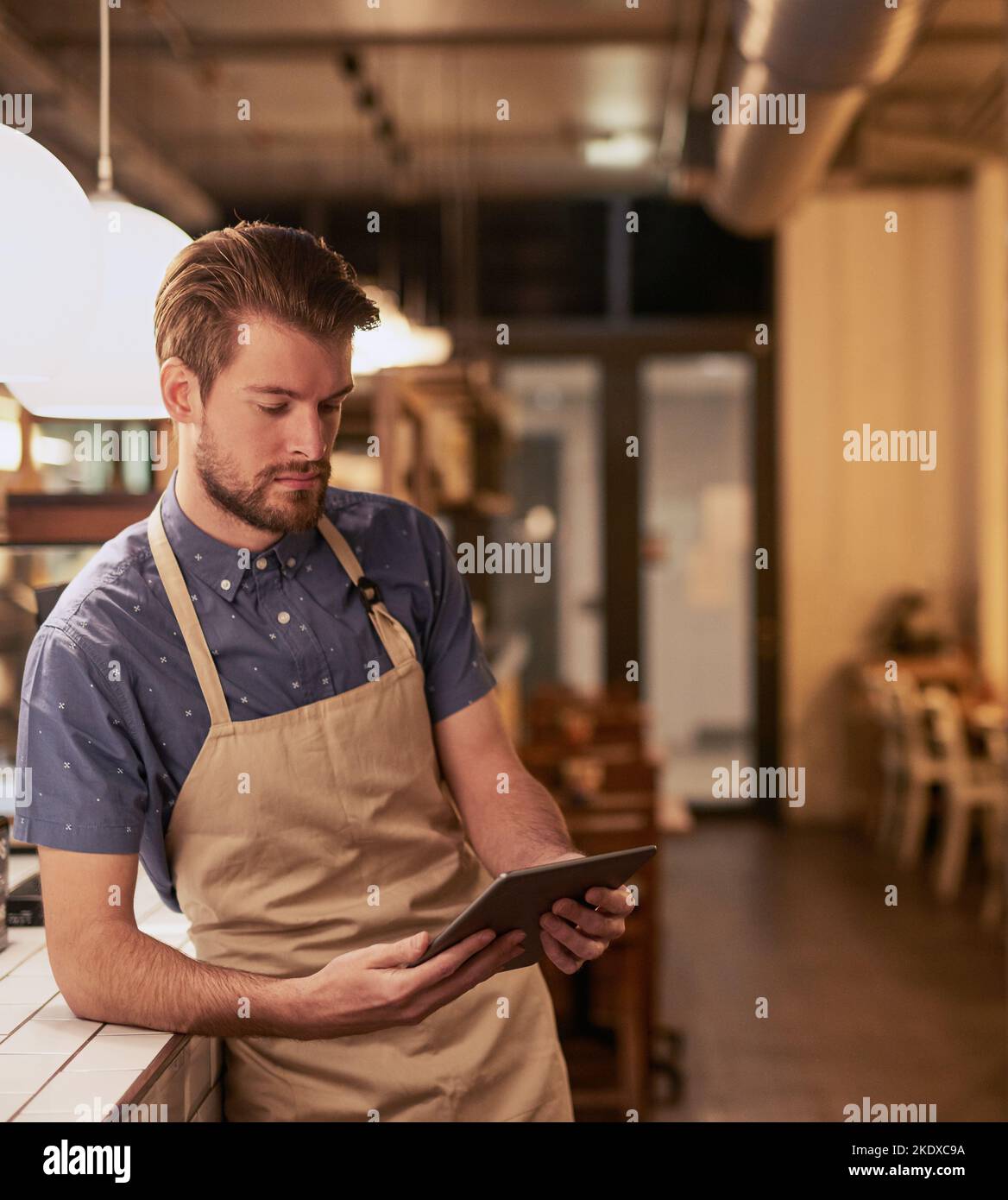 Recherche de moyens de transformer votre petite entreprise Vérifiez en ligne. Un jeune homme utilisant une tablette numérique tout en travaillant dans un café. Banque D'Images