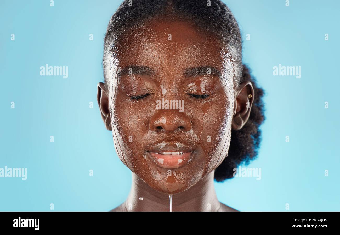 Eau, soin de la peau et visage d'une femme noire en studio pour la santé, le bien-être et l'auto-soin avec des soins cosmétiques dermatologiques. Modèle africain sur bleu Banque D'Images