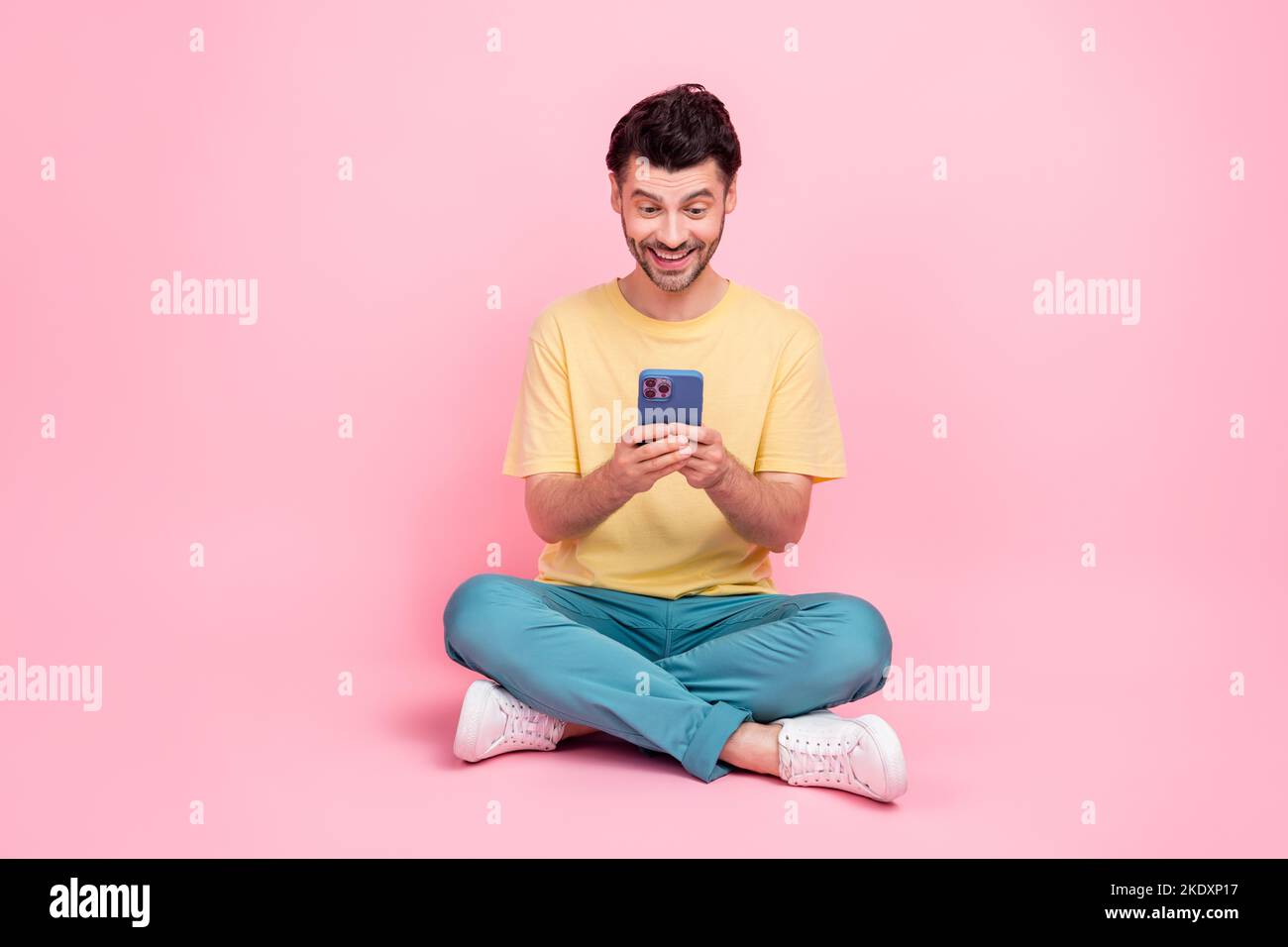 Photo de l'homme heureux positif tenir iphone regarder la vidéo chat instagram facebook twitter abonnés isolés sur fond rose couleur Banque D'Images