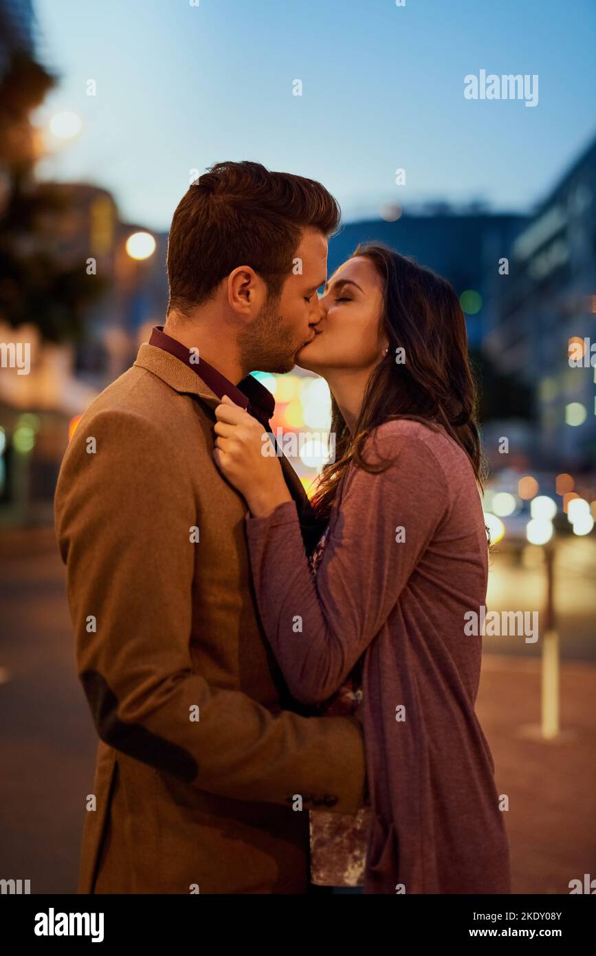 Un jeune couple affectueux qui partage un baiser dehors la nuit. Banque D'Images
