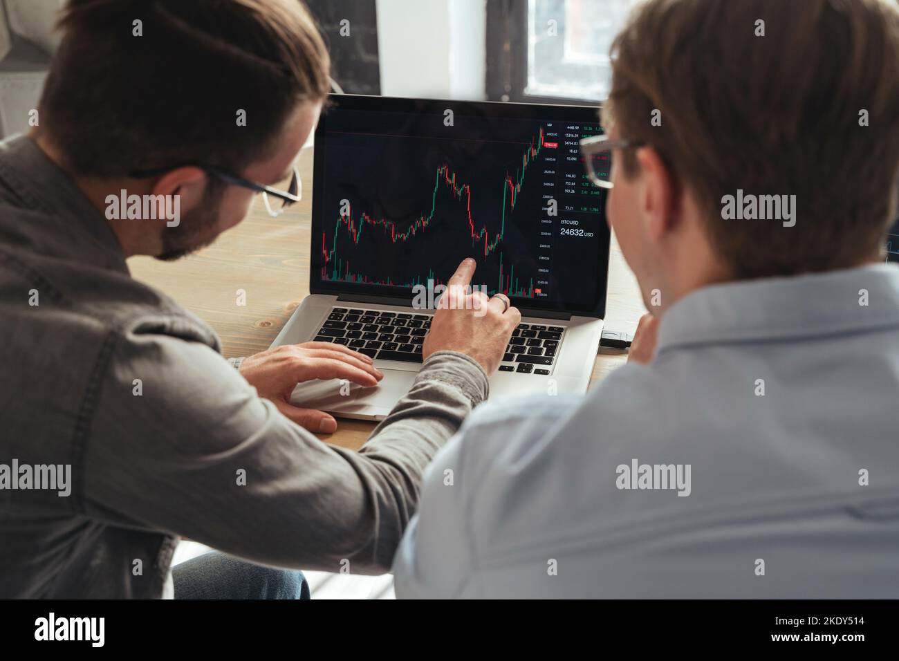 Vue d'ensemble de la table de Trader enseignant les bases de l'investissement en crypto-monnaie à ses collègues, expliquant les tendances du marché ou consultant son client, en analysant les tableaux de flux d'argent ensemble sur l'écran de pc Banque D'Images