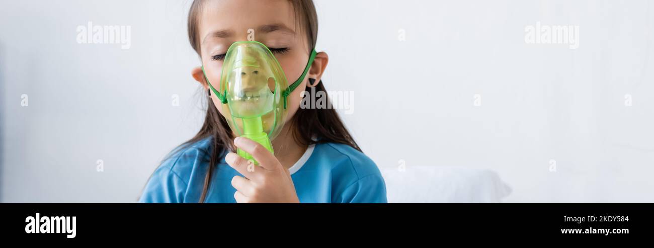 Enfant dans la robe de patient utilisant le masque d'oxygène dans la clinique, bannière, image de stock Banque D'Images