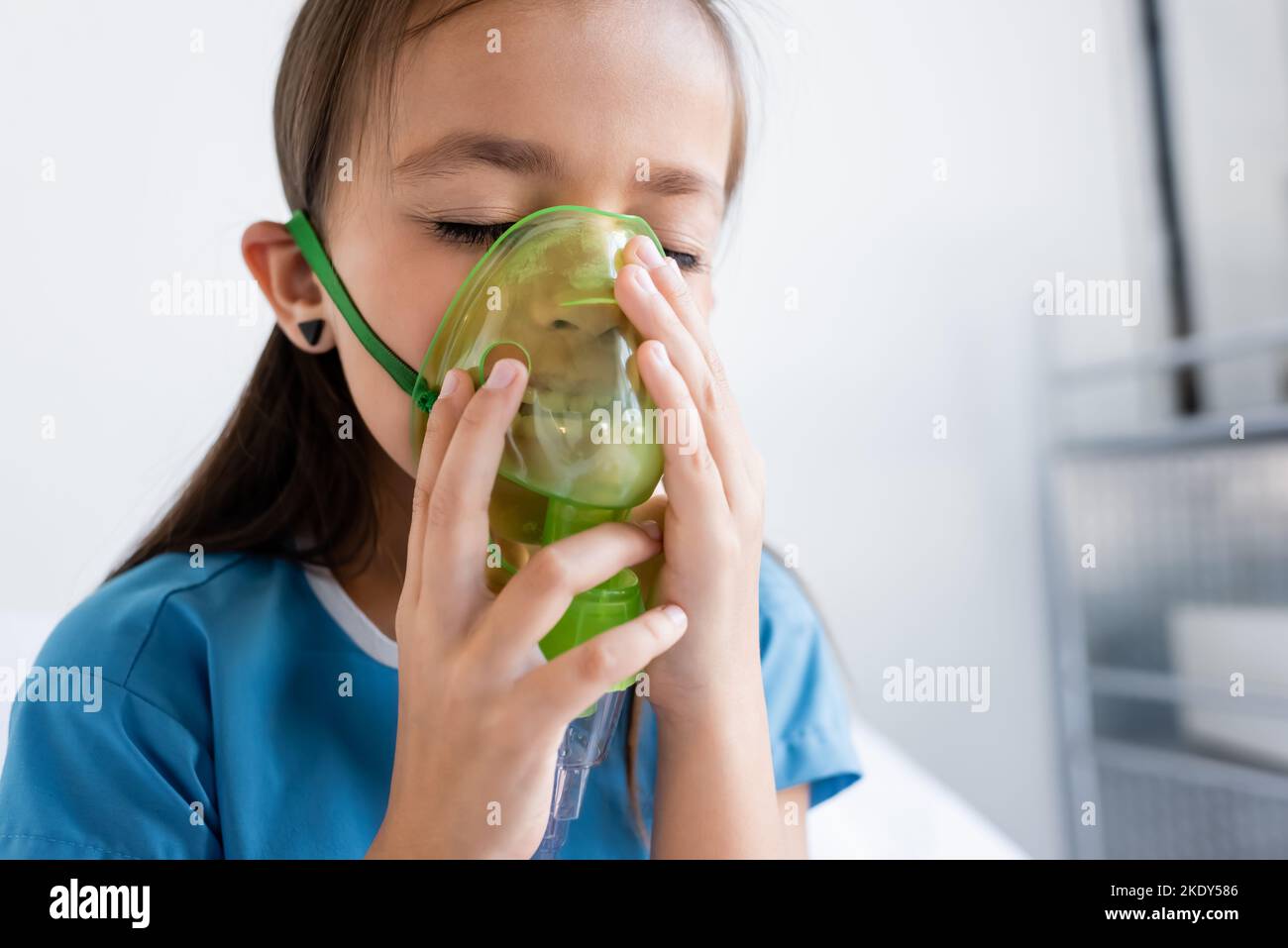 Enfant malade dans la robe de patient en utilisant le masque d'oxygène dans la clinique, image de stock Banque D'Images