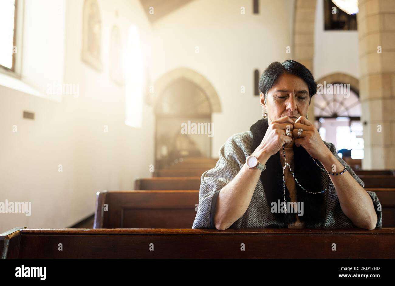 Priez, l'église et la femme âgée priant avec un rosaire dans une chapelle calme, zen seule, sainte et spirituelle. La prière, l'adoration et la dame mexicaine sont en contact avec Dieu Banque D'Images