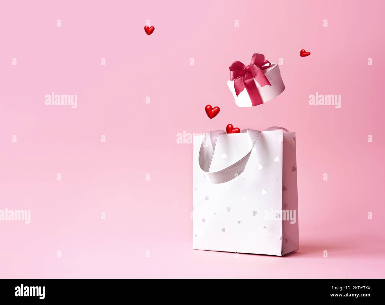 Sac à provisions avec boîte cadeau et coeurs sur fond rose. Concept de shopping et de réductions pour la Saint-Valentin Banque D'Images