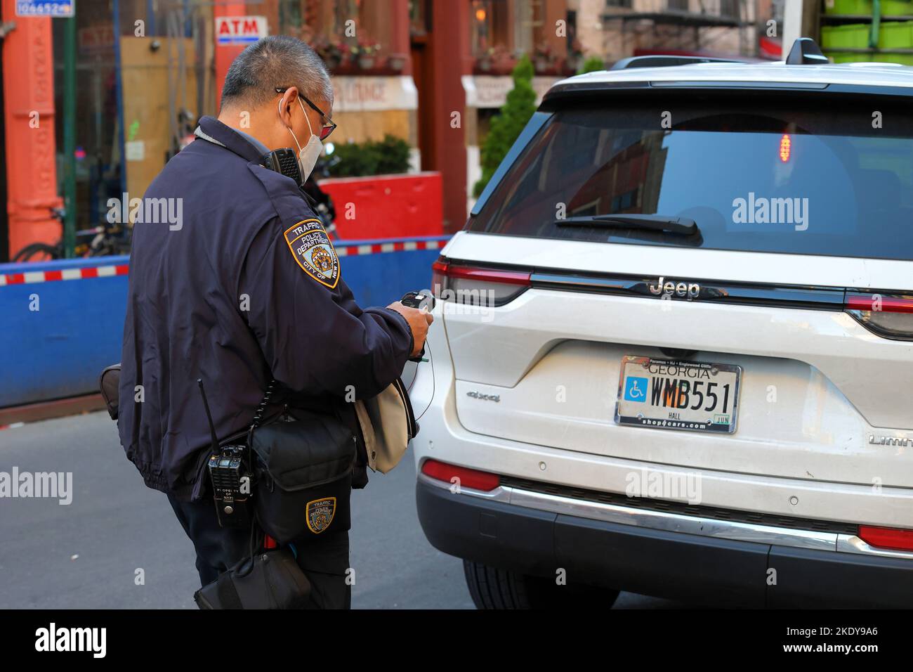 Un agent d'application de la réglementation NYC Traffic scanne une plaque d'immatriculation à l'aide d'un périphérique sans fil portatif offrant un accès en temps réel aux informations relatives aux billets de stationnement. Banque D'Images