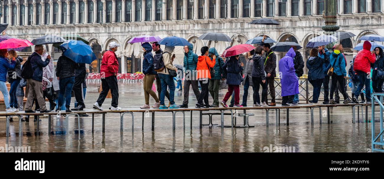 Les touristes à la pluie à l'aide de Venise à marcher à travers un caillebotis a inondé la place St Marc à marée haute Banque D'Images