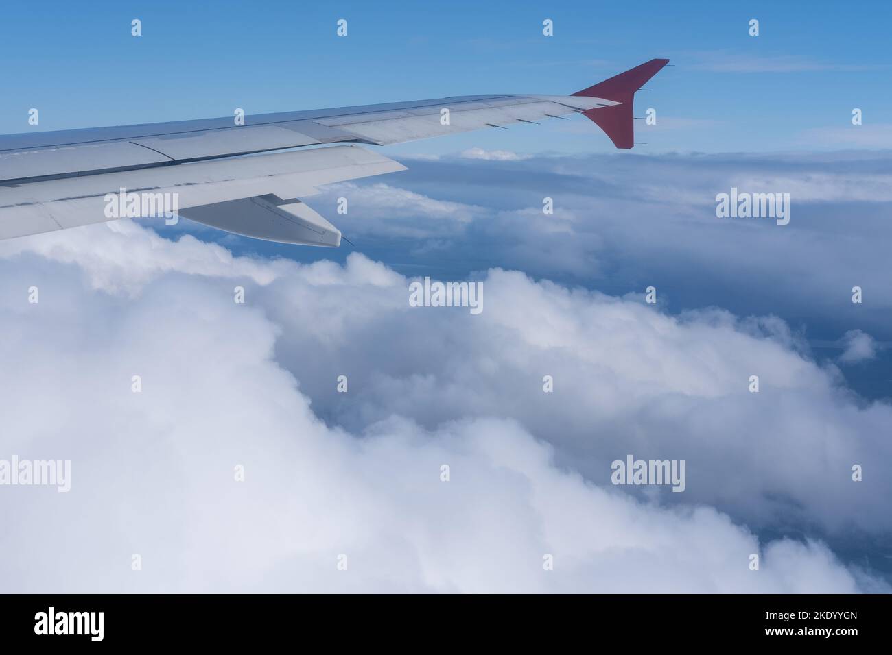 La vue de la fenêtre de l'avion sur l'aile de l'avion contre le fond des nuages moelleux et du ciel bleu. Le concept de voyage. Banque D'Images