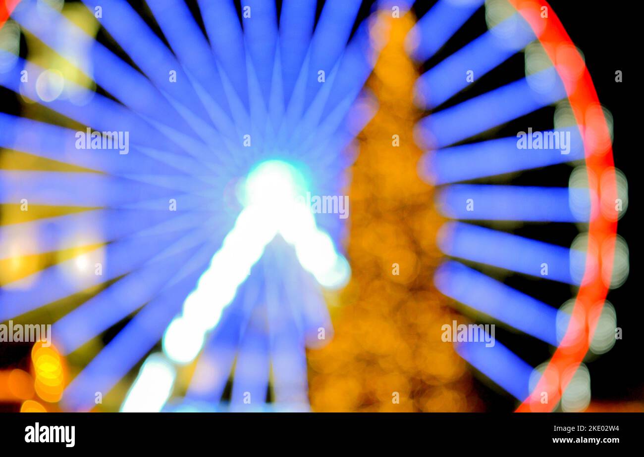 La grande roue de Ferris est illuminée de rouge et un grand arbre de ...