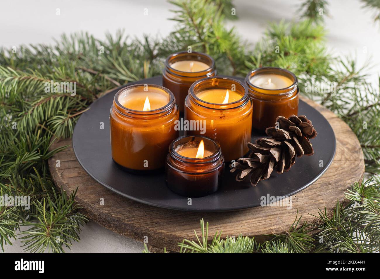 Les bougies de soja brûlent dans des pots en verre. Confort à la maison. Bougie dans un pot brun. Parfum et lumière. Bougie parfumée faite à la main. Aromathérapie. Arbre de Noël et ambiance d'hiver. Décoration chaleureuse. Décoration de fête Banque D'Images
