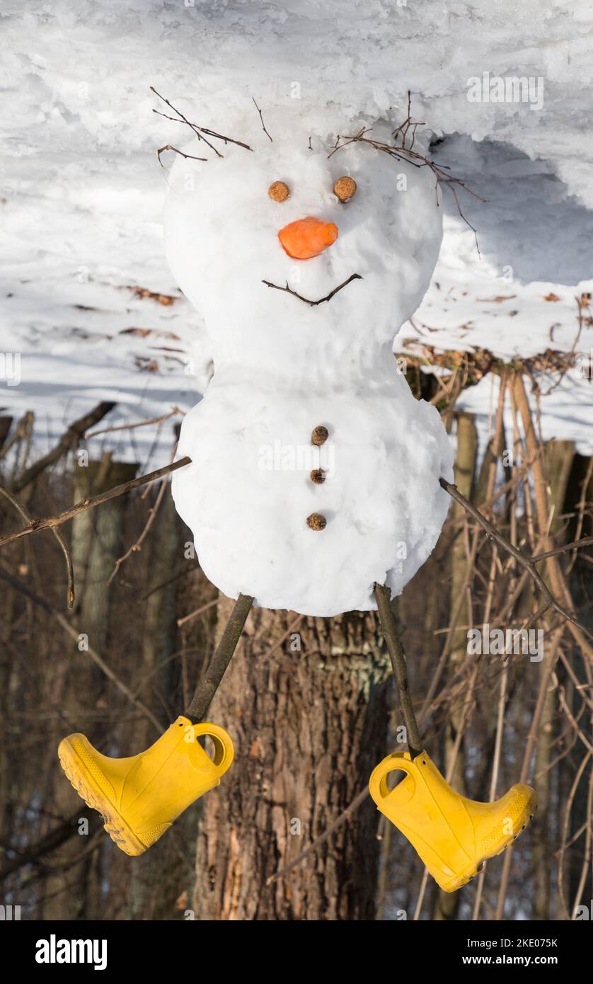 joyeux bonhomme de neige mignon en bottes jaunes à l'envers dans une forêt enneigée, à l'envers drôle de photo.Vacances en hiver. Plaisir d'hiver, Banque D'Images