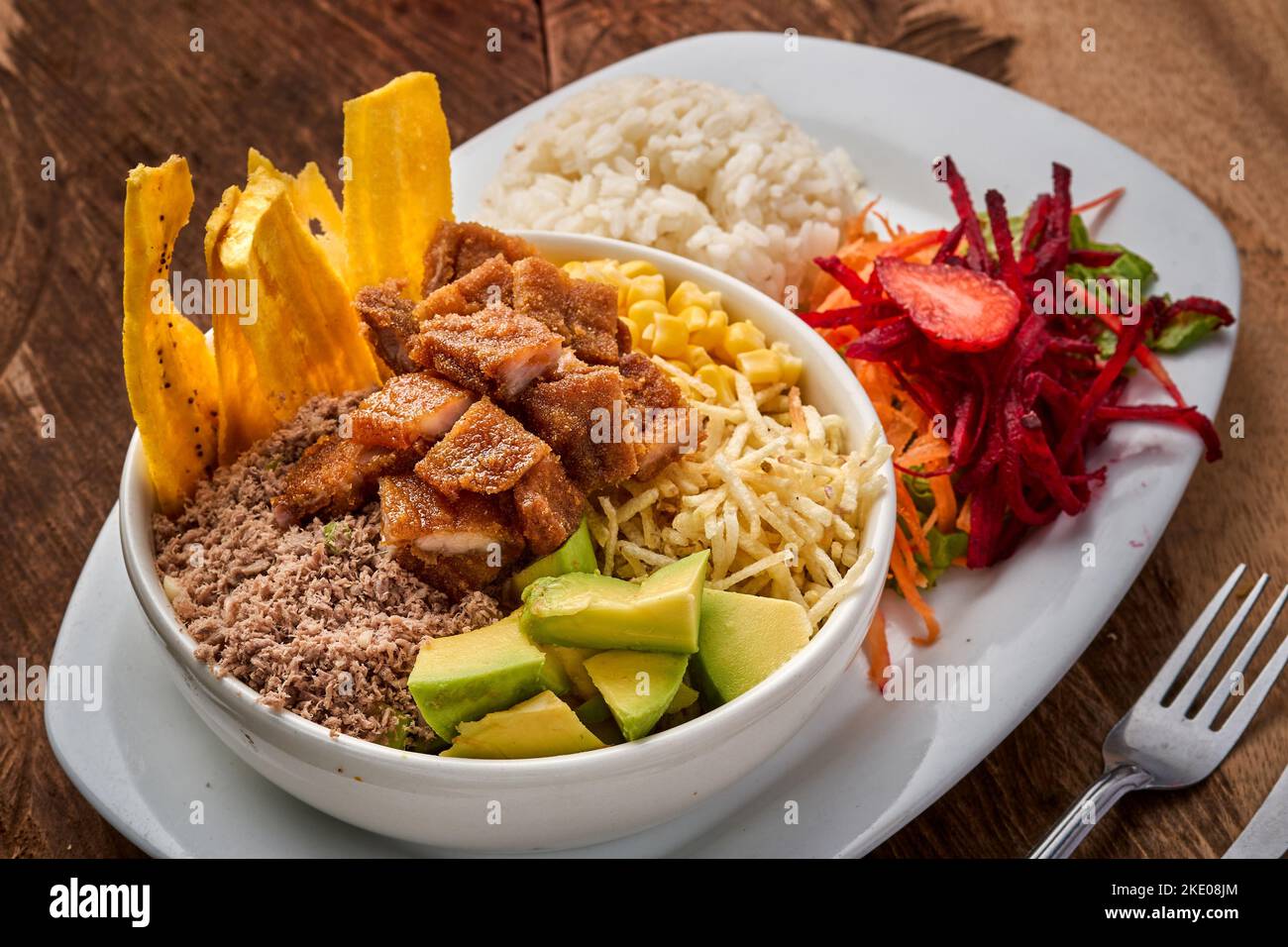 Vue de dessus d'une assiette avec un plat traditionnel de Bandeja Paisa avec salade de légumes sur une table en bois Banque D'Images