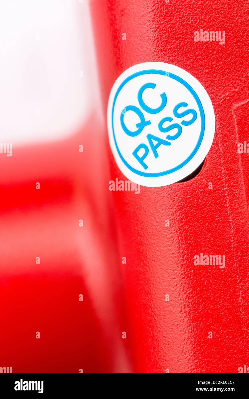 Gros plan de l'étiquette de papier adhésif QC Pass en papier bleu et blanc sur le côté du produit générique fabriqué en chinois. Pour passer le contrôle qualité, concept de CQ. Banque D'Images