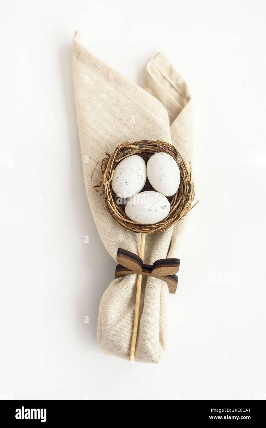 Nid décoratif en osier avec œufs et serviette pliée sur blanc Banque D'Images