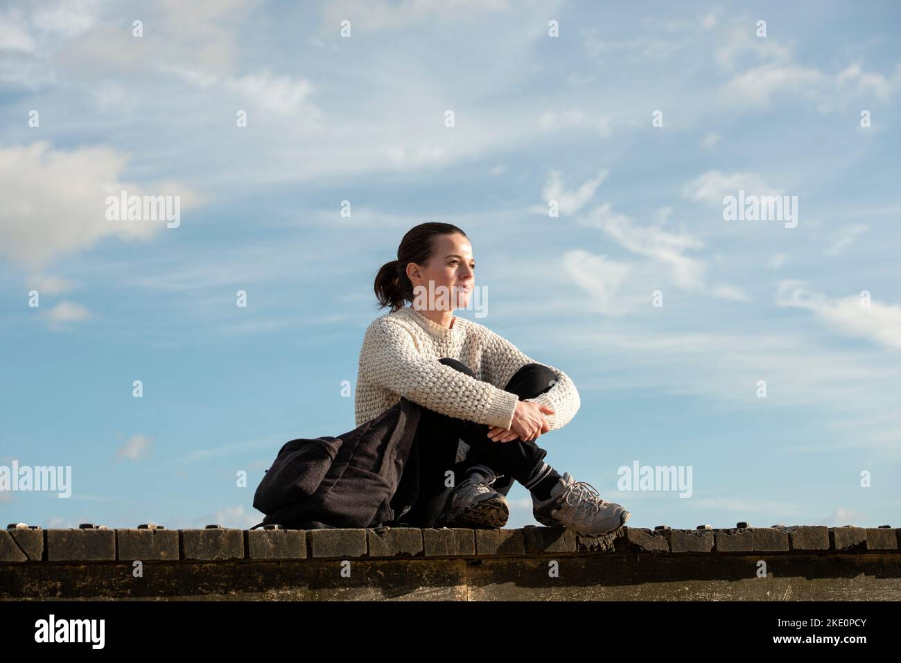 femme assise à l'extérieur au bord de l'océan, profitant de la vue. Banque D'Images