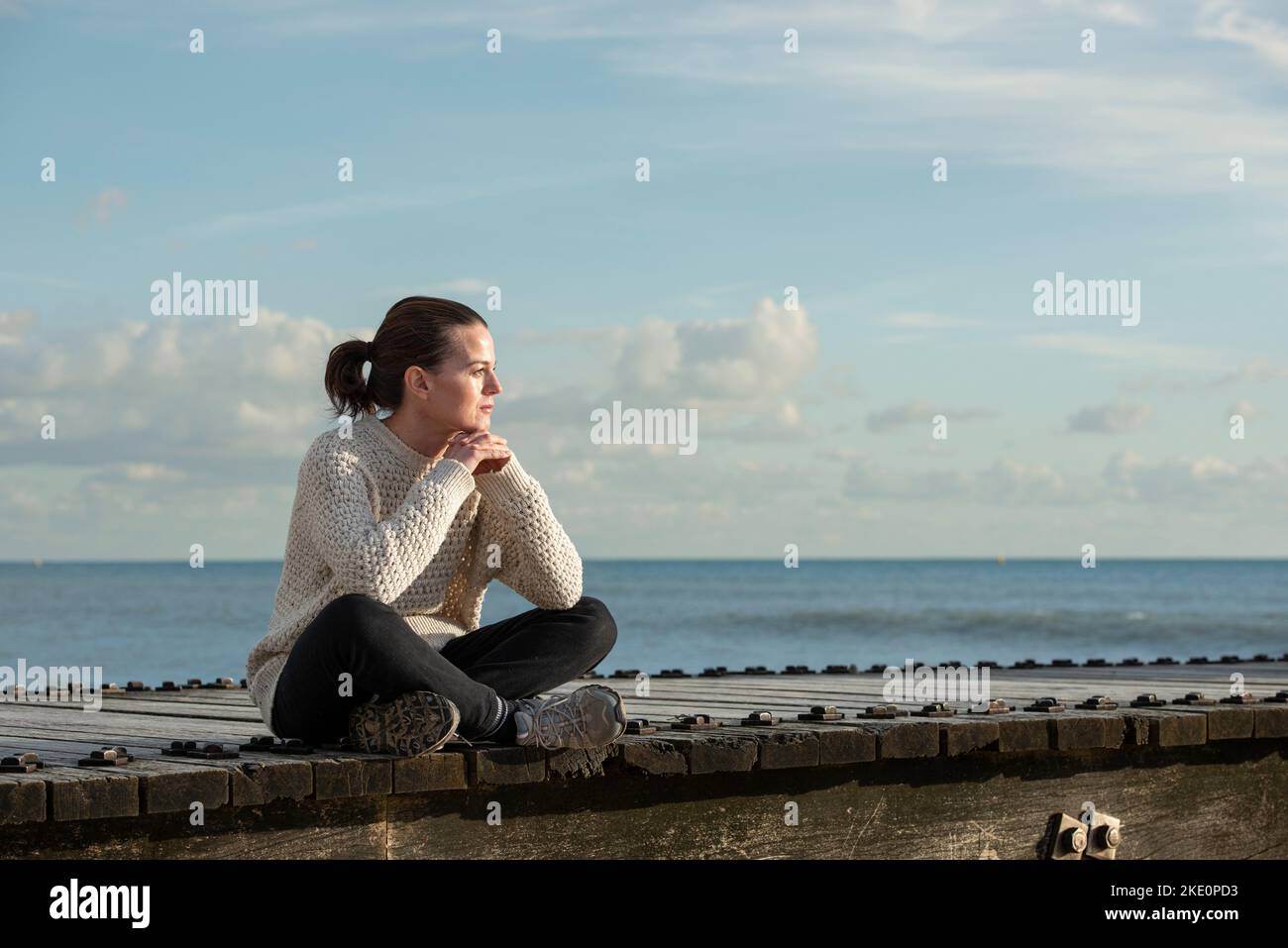 femme assise à l'extérieur au bord de l'océan, profitant de la vue. Banque D'Images