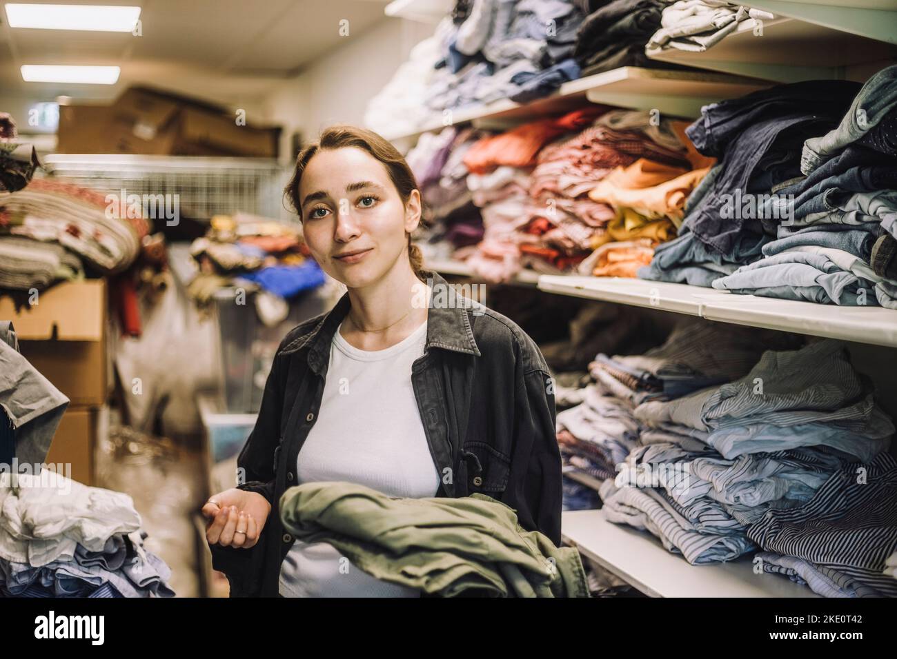 Portrait d'une jeune femme de mode debout près de l'étagère à vêtements à l'atelier Banque D'Images