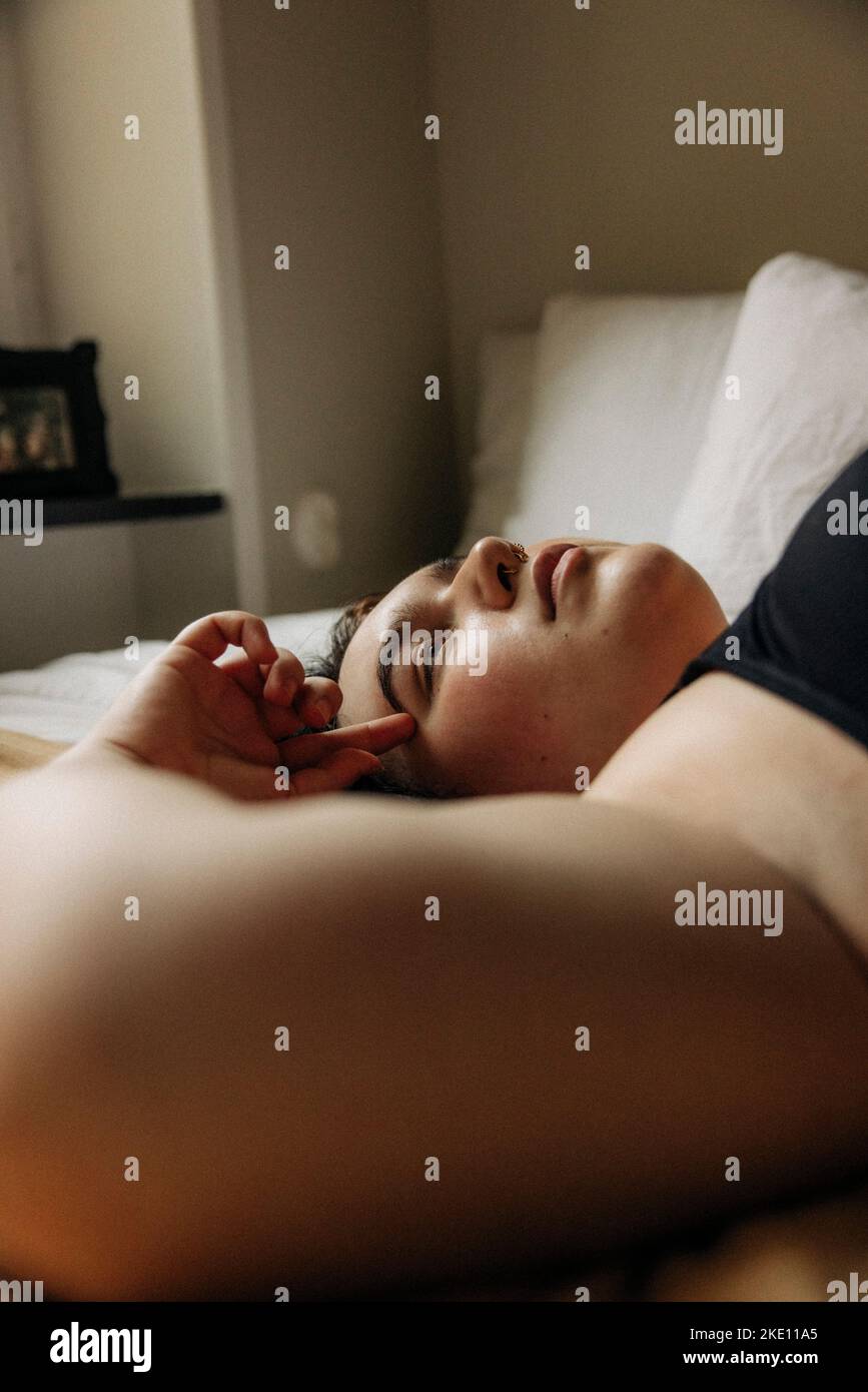 Young woman lying on bed at home Banque D'Images