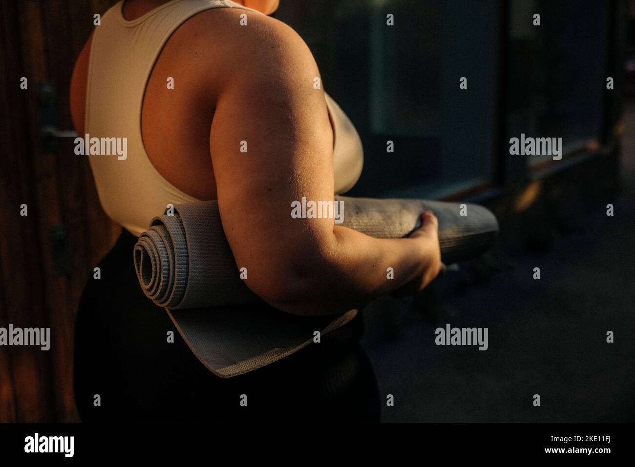 Vue arrière d'une femme voluptueuse avec tapis d'exercice au coucher du soleil Banque D'Images
