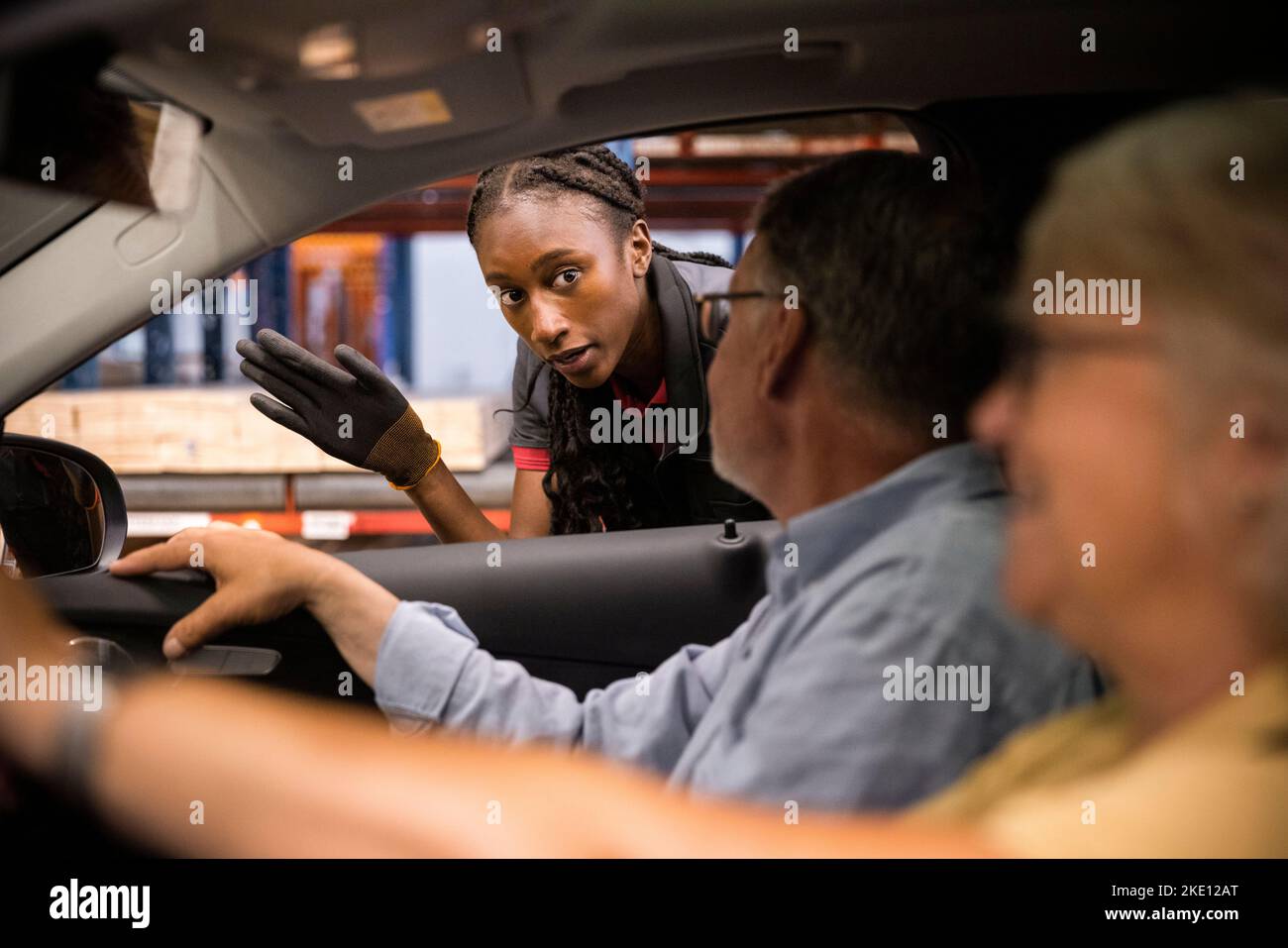 Le personnel de vente guide les clients assis dans la voiture dans un magasin de matériel Banque D'Images