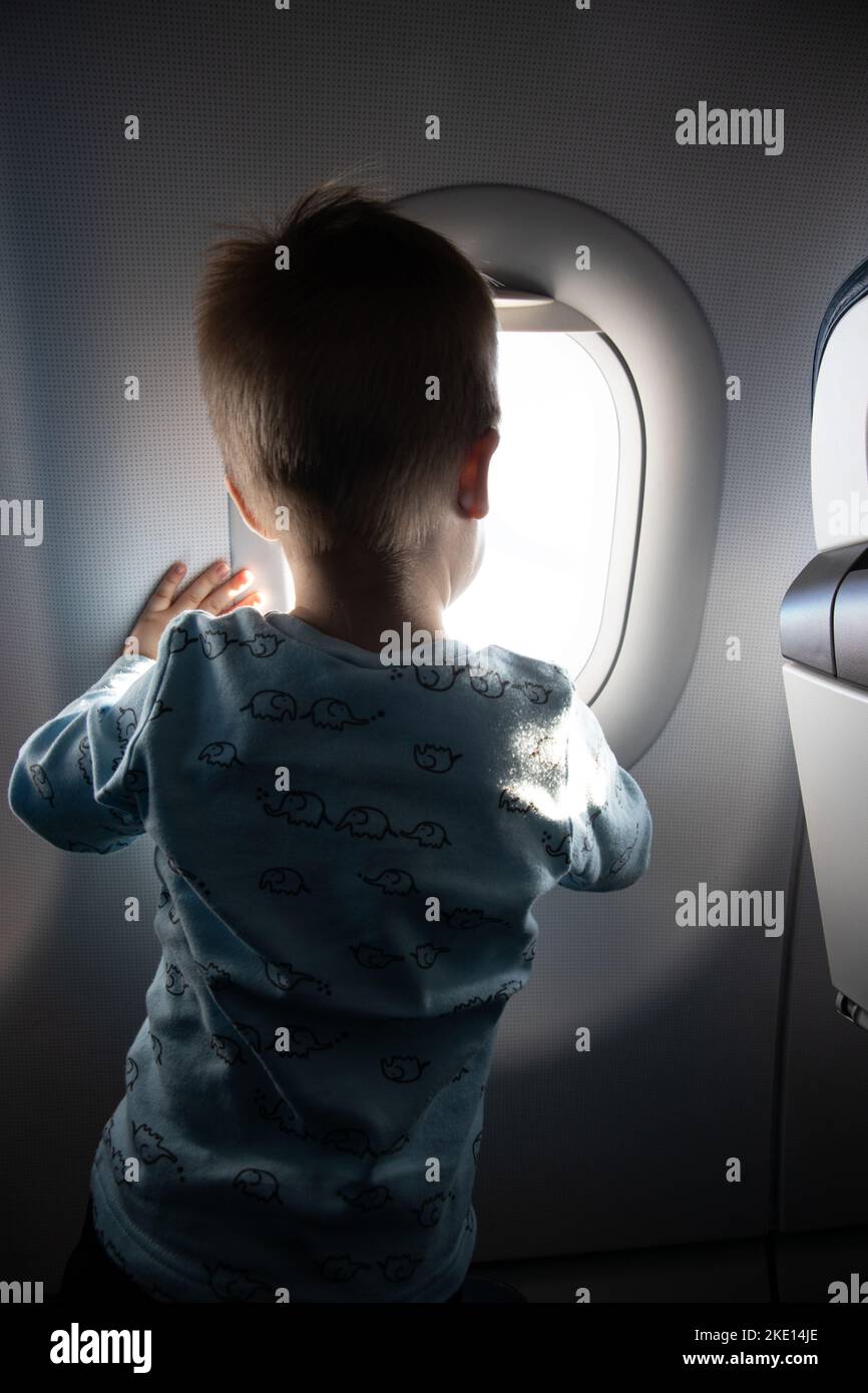 Petit garçon regardant par la fenêtre de l'avion Banque D'Images