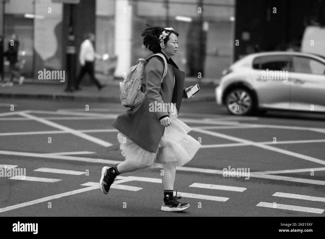 Une fille asiatique vêtue de vêtements modernes court dans les rues de Londres Banque D'Images