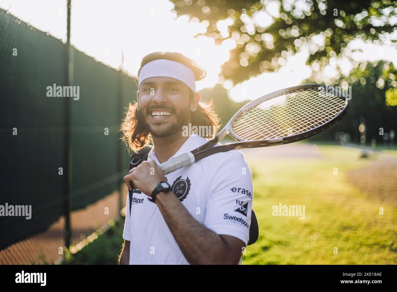 Portrait d'un homme souriant tenant une raquette de tennis Banque D'Images
