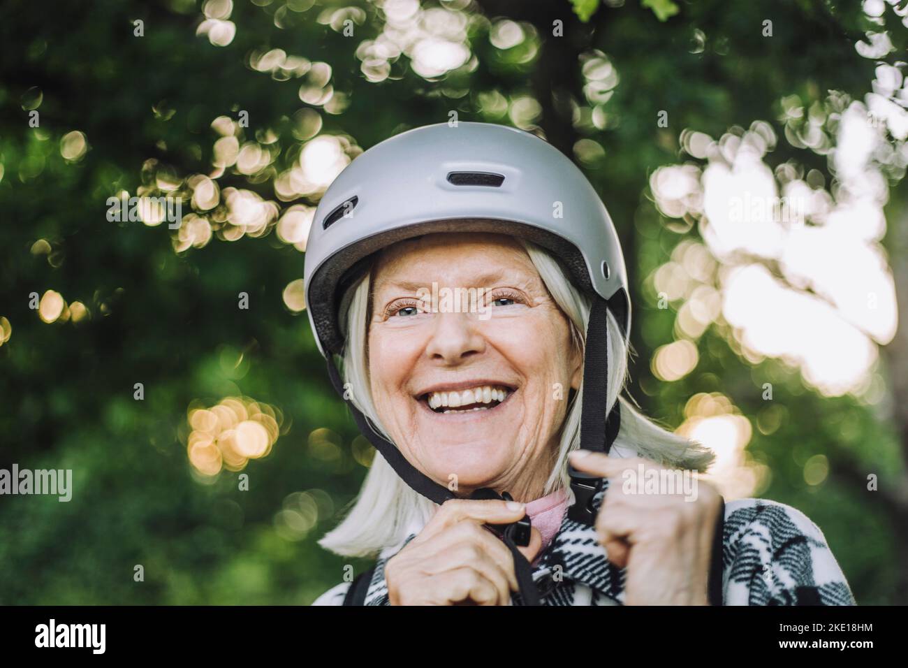Bonne femme âgée qui cherche à porter un casque de sport Banque D'Images