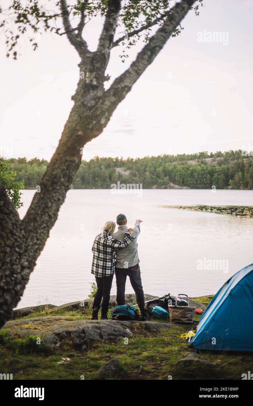 Femme debout avec un homme regardant la vue depuis le bord du lac Banque D'Images
