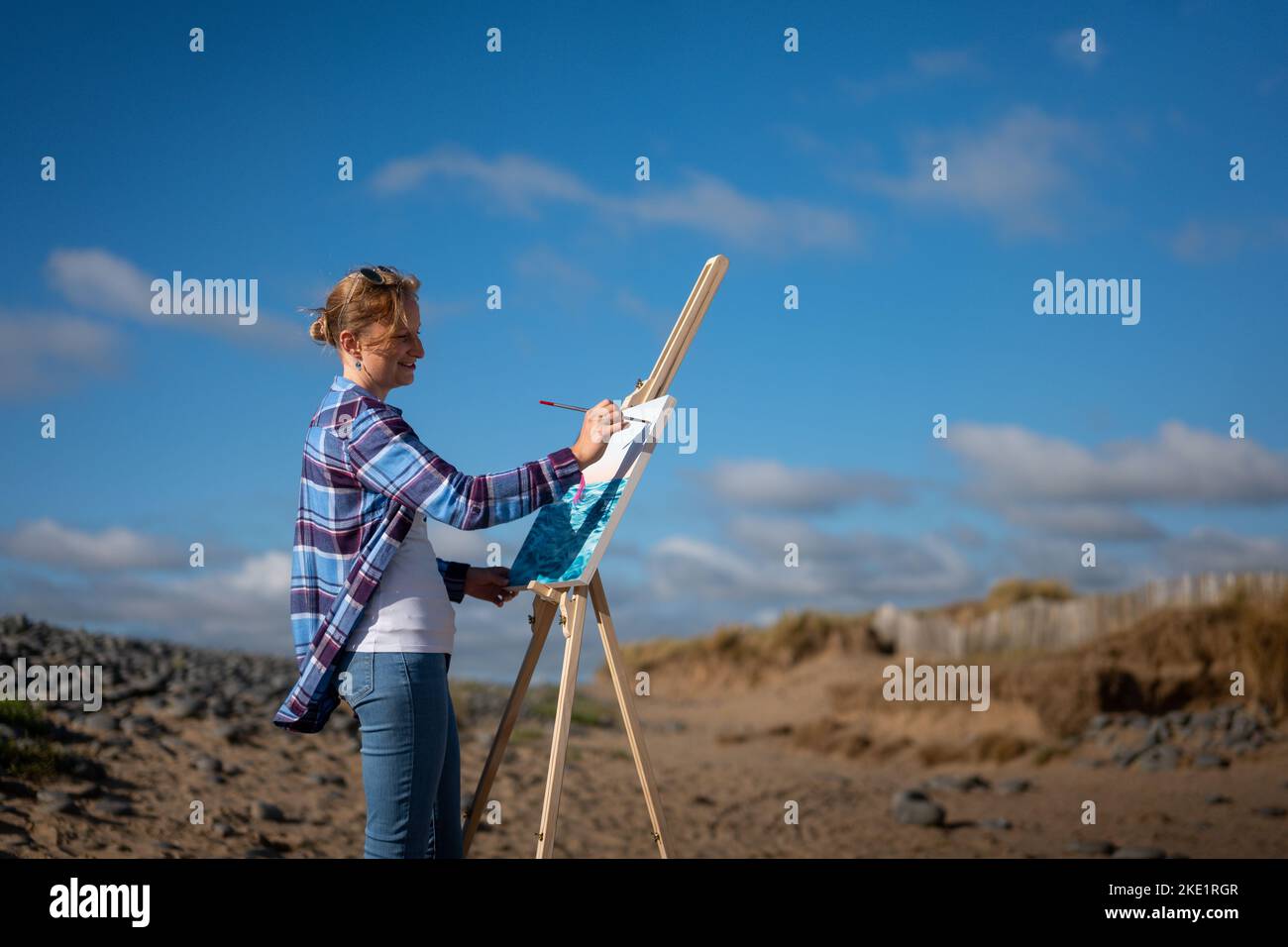 L'artiste Clare Willcocks, photographié travaillant sur la plage de Sandymere, North Devon. Banque D'Images
