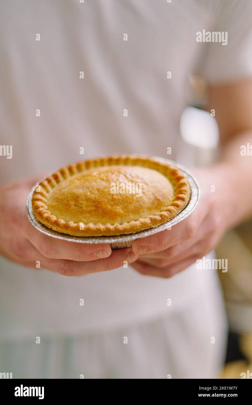 Tarte et pasties à vendre dans une boulangerie, mains tenant une tarte Banque D'Images