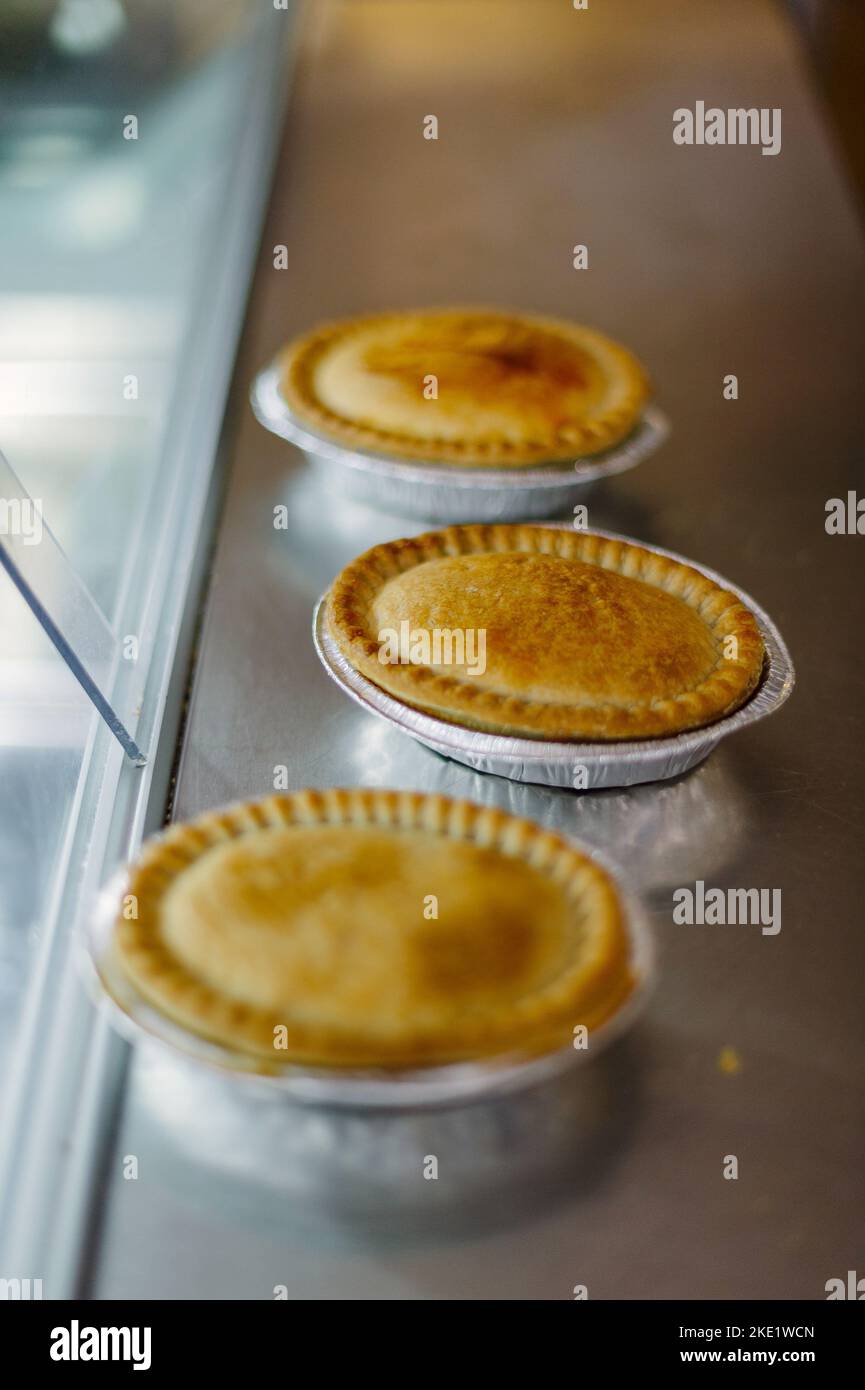 Tarte et pasties à vendre dans une boulangerie, mains tenant une tarte Banque D'Images