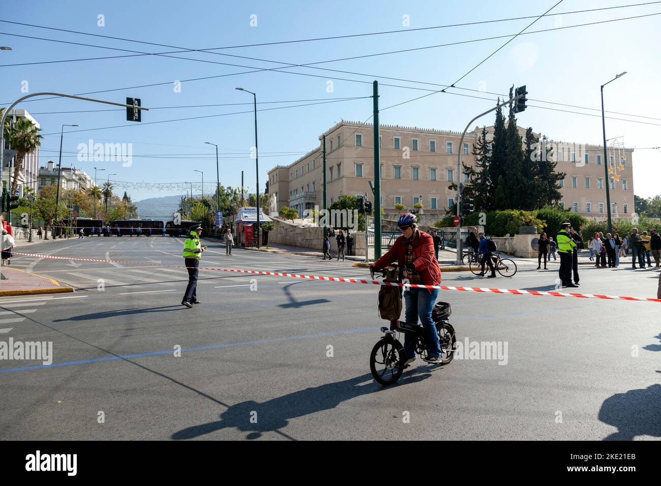 Le vieil homme qui fait du vélo rencontre un ruban rouge interdisant la circulation en raison des restrictions imposées par la police lors d'une manifestation anti-gouvernementale massive. Banque D'Images
