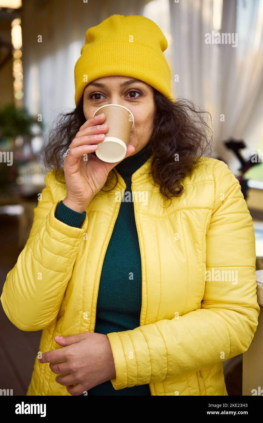 Jolie femme en chandail vert et chapeau et veste jaune vif prenant une  gorgée de café à emporter arôme chaud dans une tasse en papier Photo Stock  - Alamy