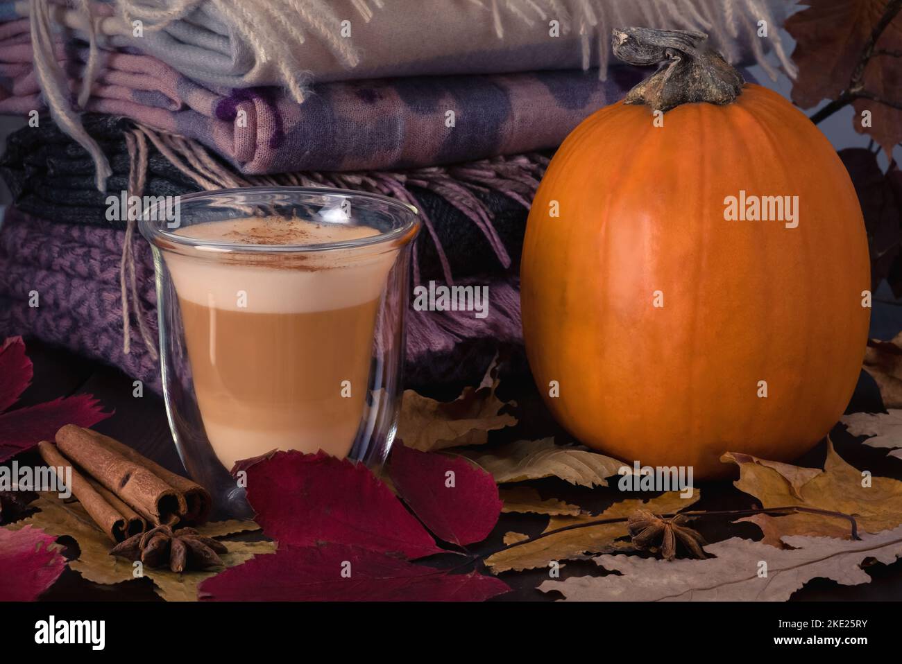 Tasse en verre avec latte de citrouille et support de citrouille mûr sur table Banque D'Images