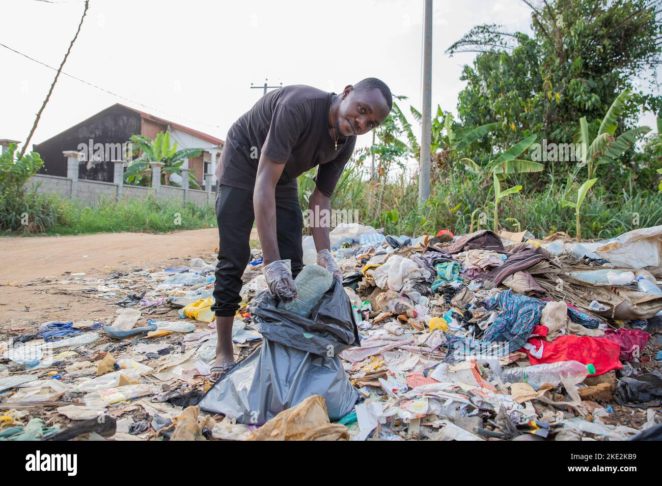 Un jeune homme africain regarde la caméra tout en collectant les déchets du sol. Banque D'Images