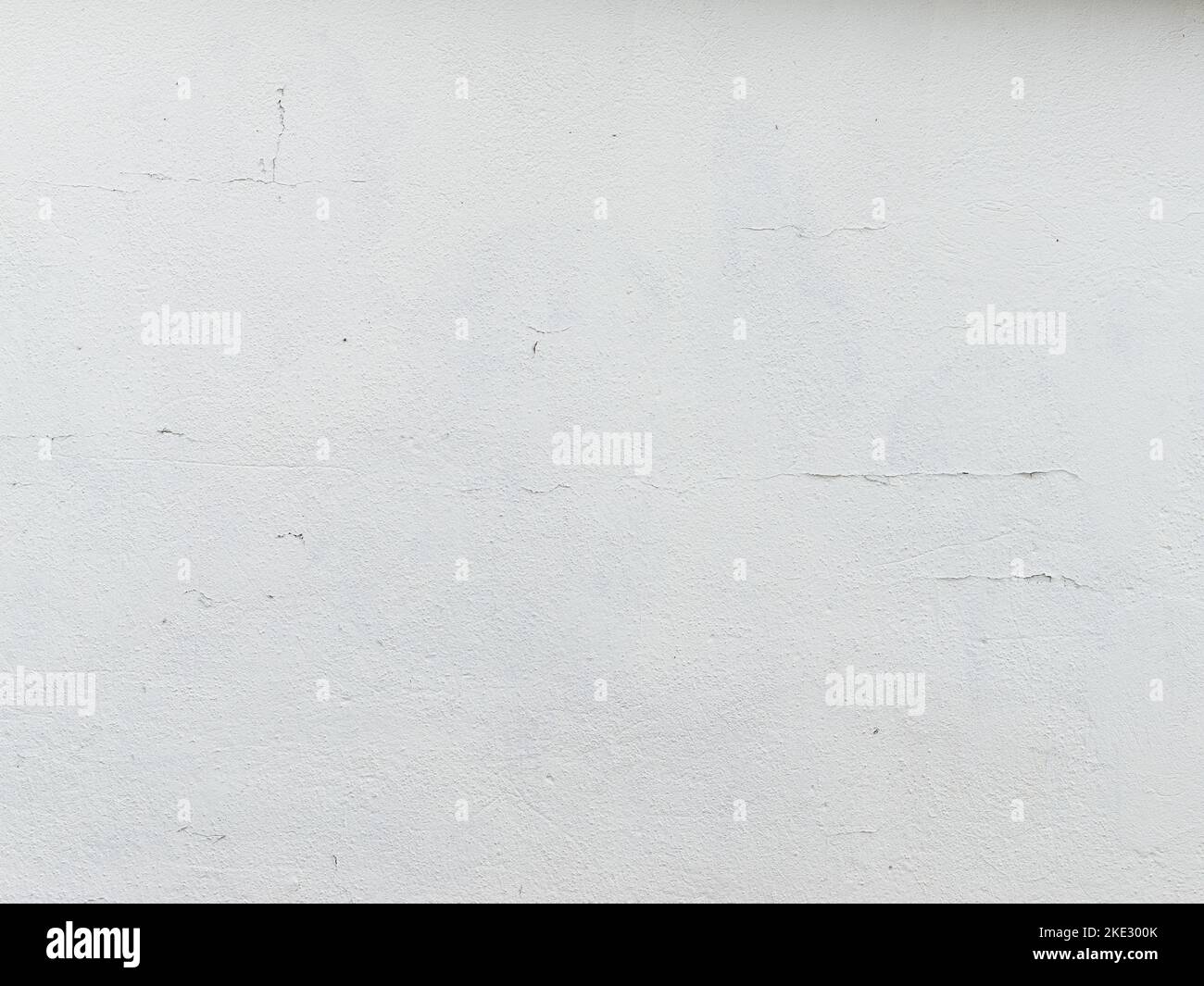 Vieux plâtre blanc sur une façade de maison. Texture d'arrière-plan plein format avec petites fissures et taches de saleté. Vue rapprochée de l'extérieur du bâtiment avec des intempéries. Banque D'Images
