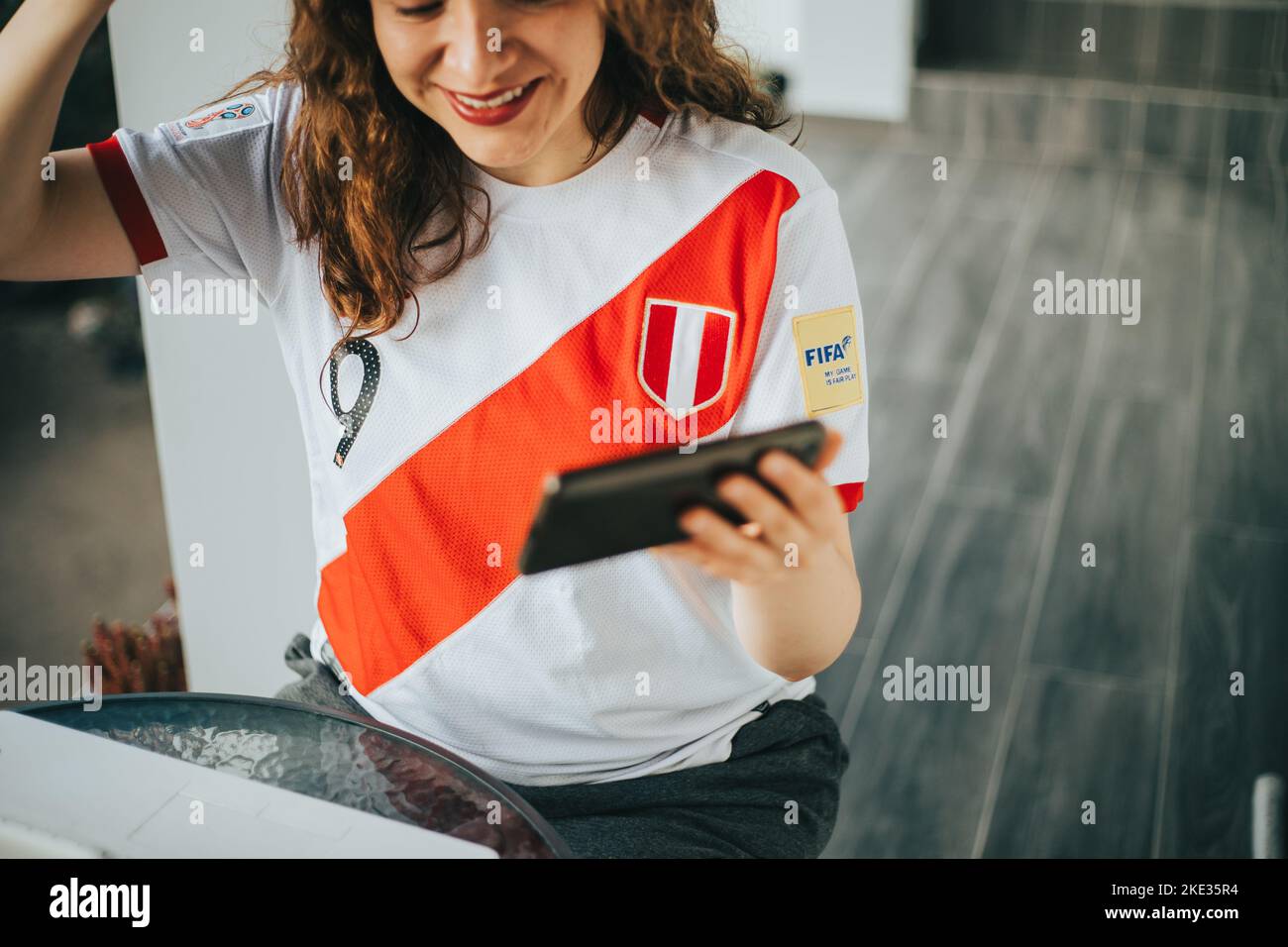Fan péruvien de football réagissant avec enthousiasme à un match de football en regardant son téléphone cellulaire. Concept de personnes et de sports. Banque D'Images