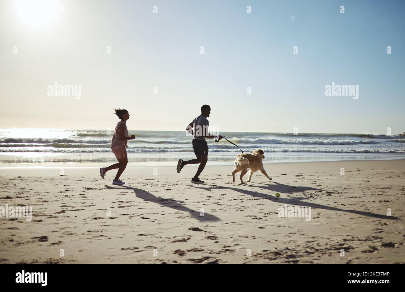 Fitness, course à pied et chien avec un couple à la plage pour la santé de la liberté et l'exercice d'été. Sports, bien-être et détente avec l'homme et la femme coureur avec les animaux de compagnie Banque D'Images
