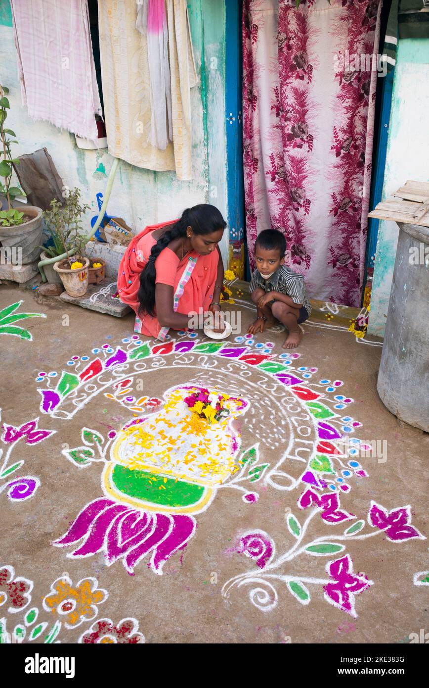Indian woman making Rangoli poudre colorée festival designs à Sankranti dans un village-rue. L'Andhra Pradesh, Inde Banque D'Images