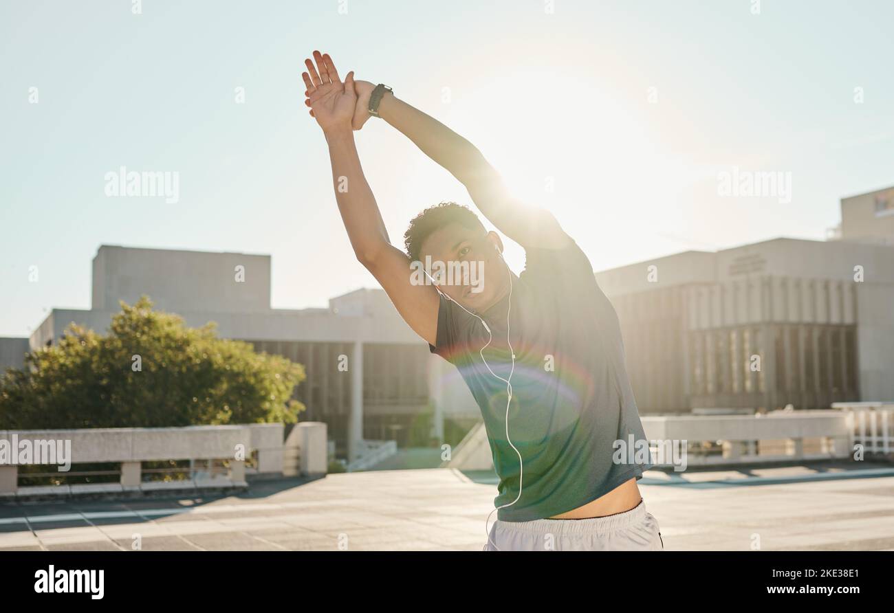Fitness, stretching et musique avec un sportif dans une ville pour la course, la santé et le matin cardio, zen et mentalité. Homme sportif, bras extensible et podcast Banque D'Images