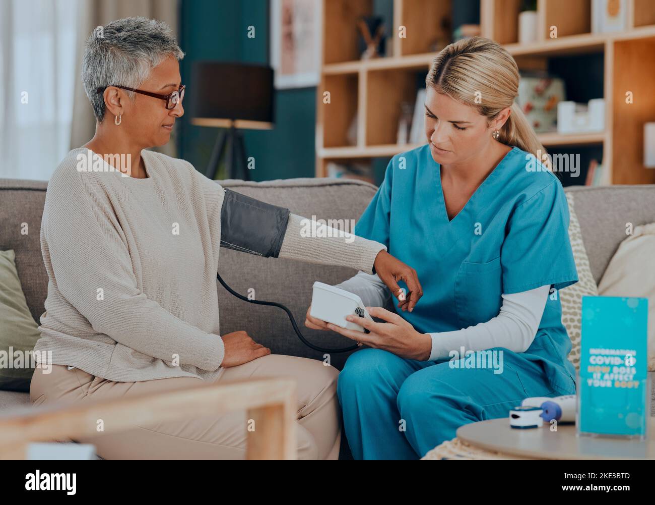 Test, consultation et médecin avec un patient pour l'examen de la tension artérielle, les soins de santé et les soins en maison de soins infirmiers sur le canapé. Médical, de soutien et senior Banque D'Images