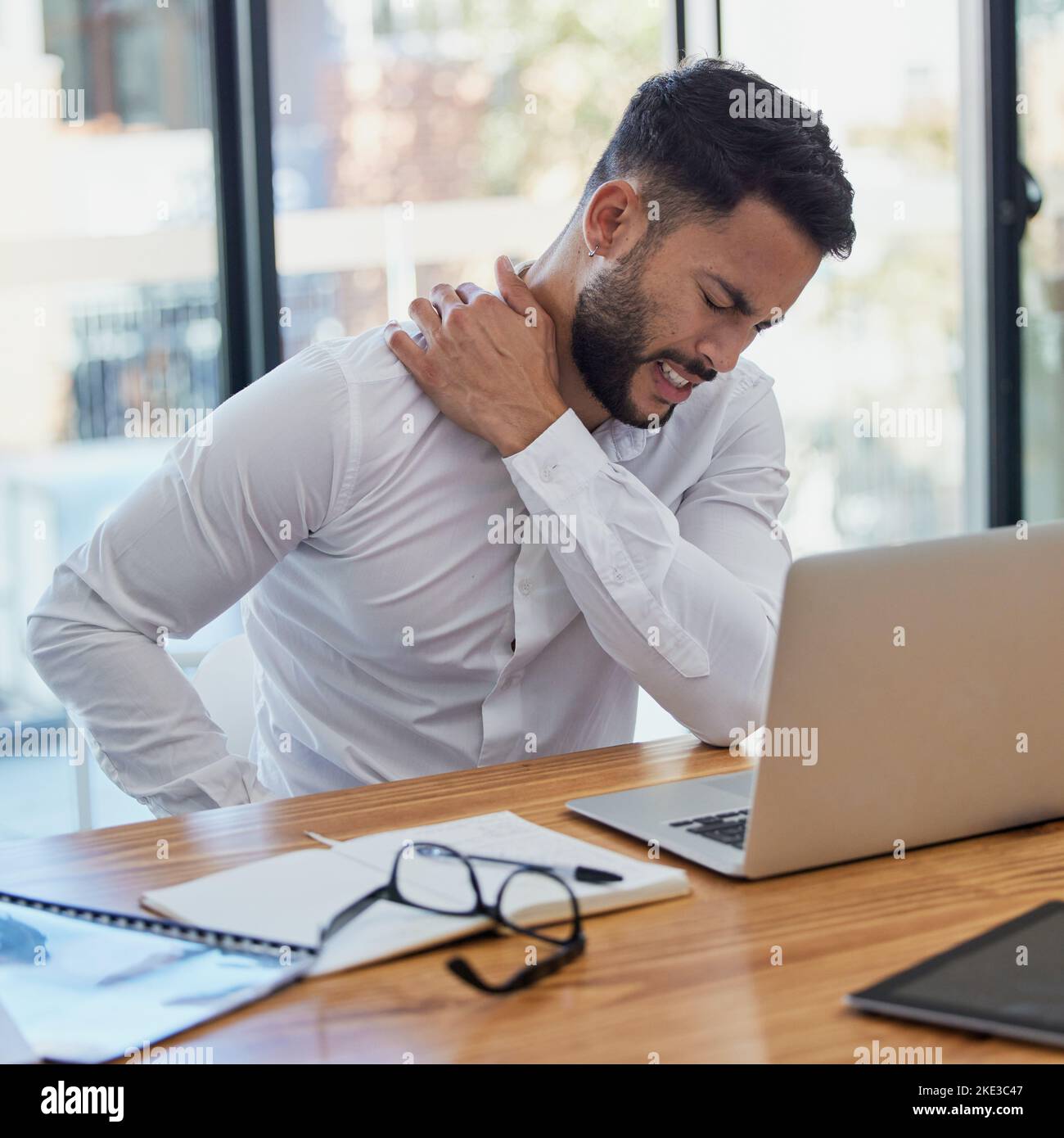 Homme, douleur d'épaule et ordinateur portable pendant le travail au bureau souffrant de stress, de dépression et de l'épuisement professionnel au bureau. Homme d'affaires arabe assis pour massosser le corps Banque D'Images