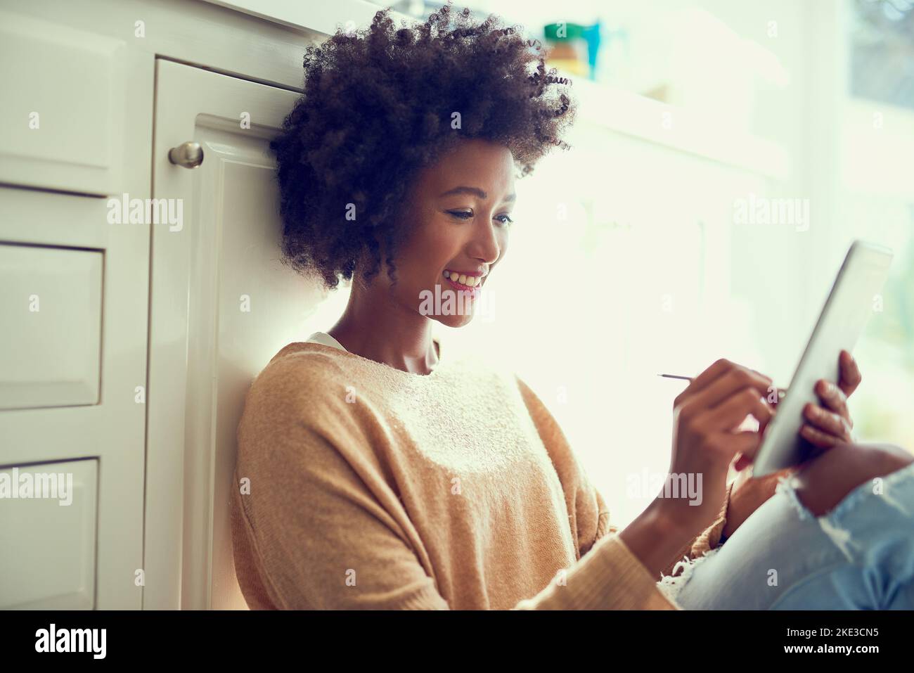 La numérisation de ses dessins. Une jeune femme utilisant une tablette numérique à la maison. Banque D'Images